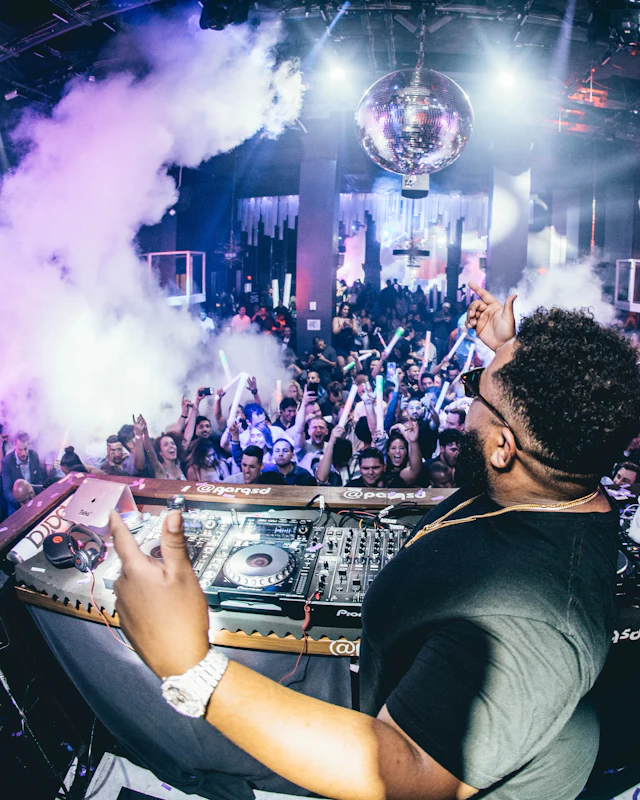 A DJ at the turntables with smoke and a mirror ball